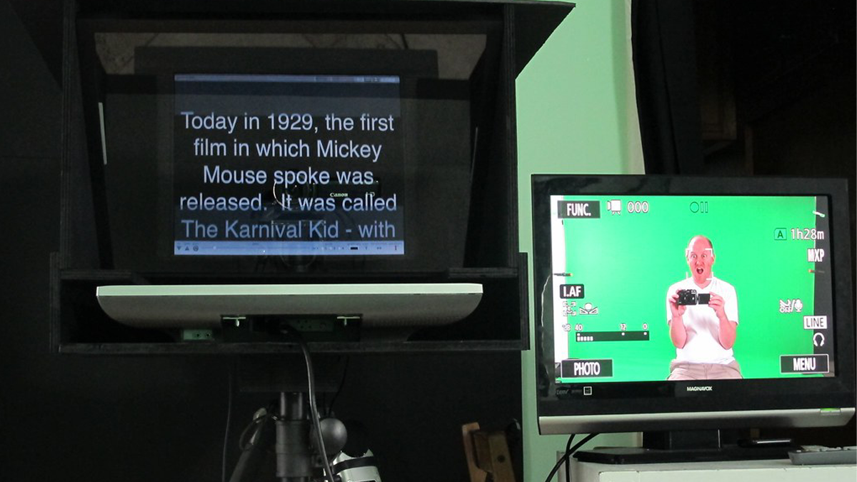 A teleprompter and person reading from it on camera
